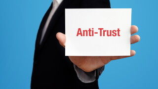 Anti-Trust. Geschäftsmann im Anzug hält Karte in die Kamera. Der Begriff Anti-Trust steht im Schild. Symbol für Business, Finanzen, Statistik, Analyse, Wirtschaft