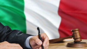 Judge writing on paper in courtroom with Italy flag background. Wooden gavel of equality theme and legal concept.
