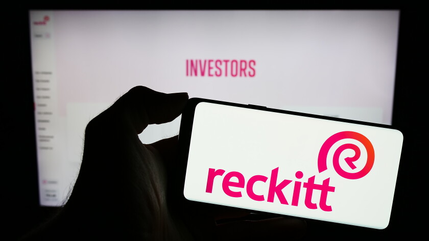 Stuttgart, Germany - 11-21-2023: Person holding mobile phone with logo of consumer goods company Reckitt Benckiser Group plc in front of business web page. Focus on phone display.