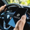 BERLIN, GERMANY JULY 2019: Uber driver holding smartphone in car. Uber is an American company offering transportation services online. Illustrative editorial.