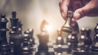 Businessman moving chess piece on chess board game concept for i