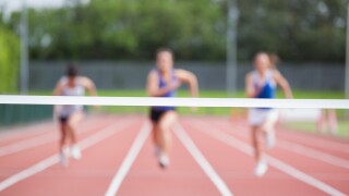 Female athletes running towards finish line on track field