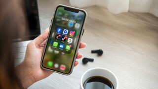 Woman holding a mobile phone with social media icons on the screen