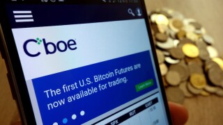 KONSKIE, POLAND - MAY 14, 2018: CBOE Global Markets website displayed on smartphone and stack of coins