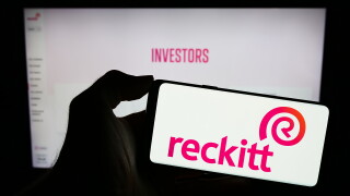 Stuttgart, Germany - 11-21-2023: Person holding mobile phone with logo of consumer goods company Reckitt Benckiser Group plc in front of business web page. Focus on phone display.